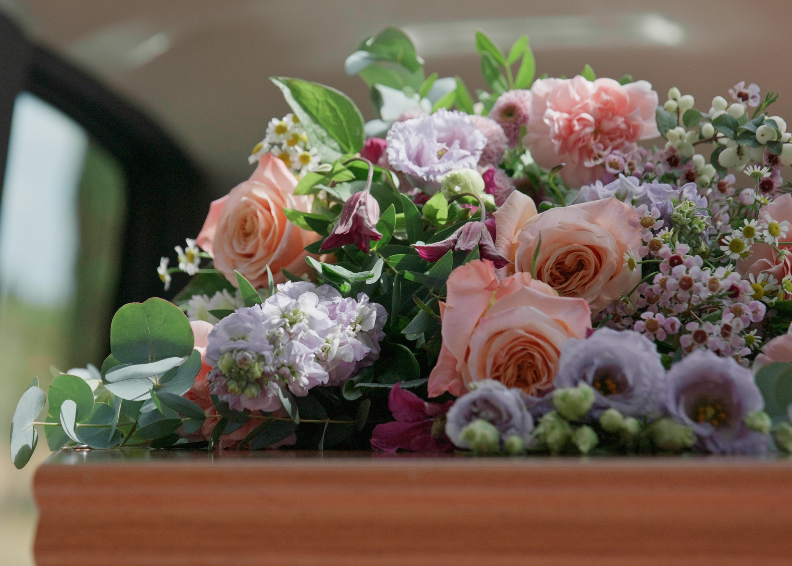 A floral tribute of peach roses and lilac blooms.